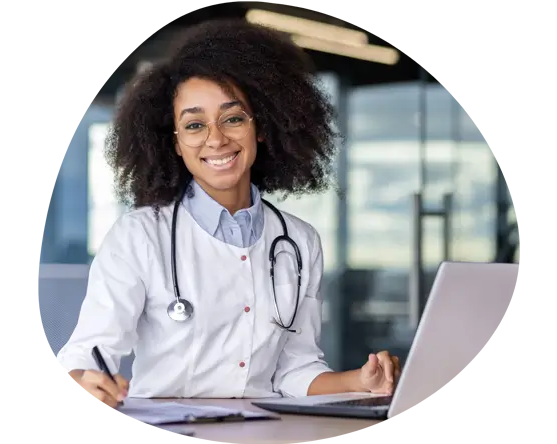 Smiling doctor with a stethoscope working on a laptop